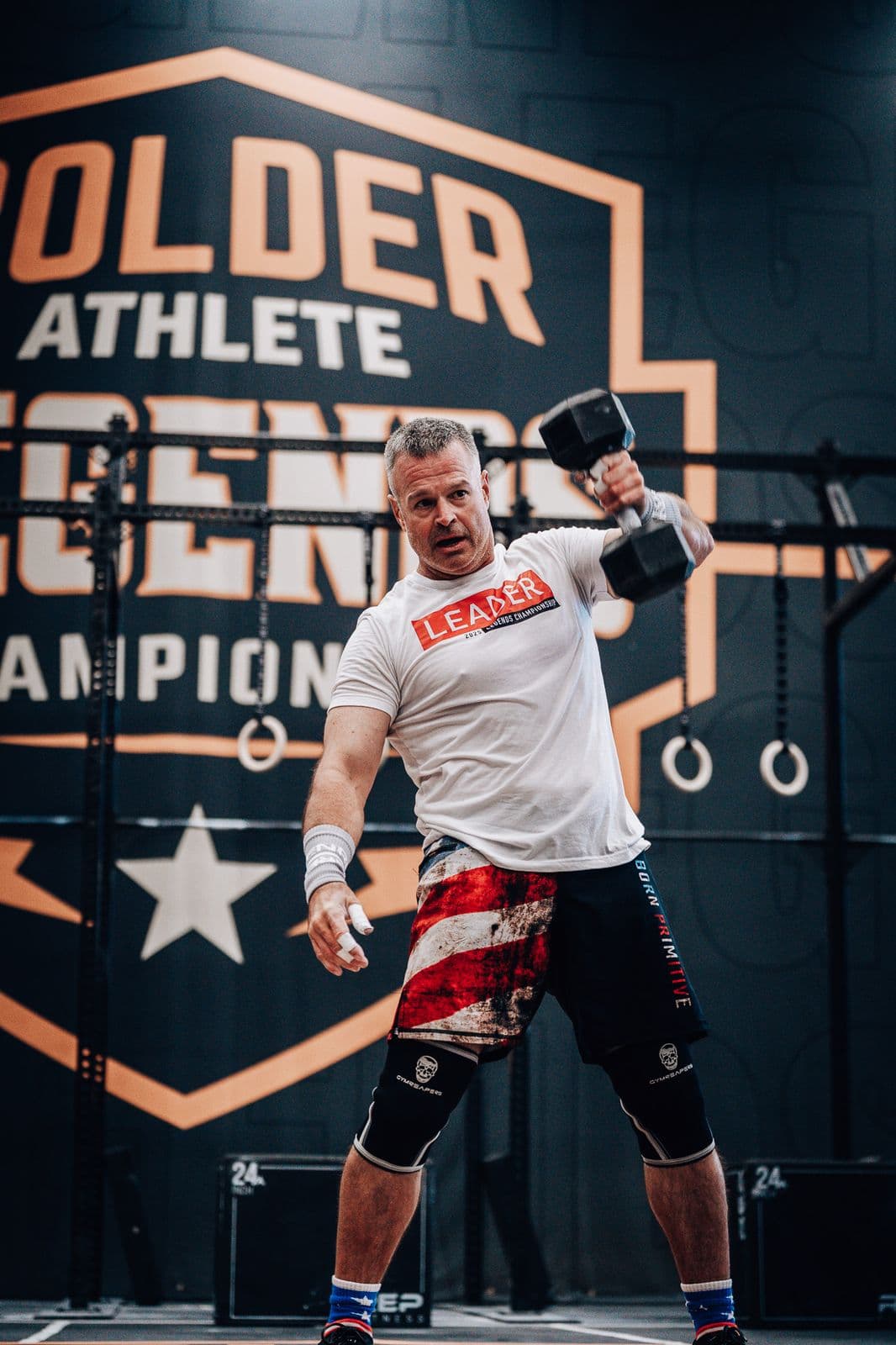 Athlete working with a dumbbell in front of a Bolder Athlete banner