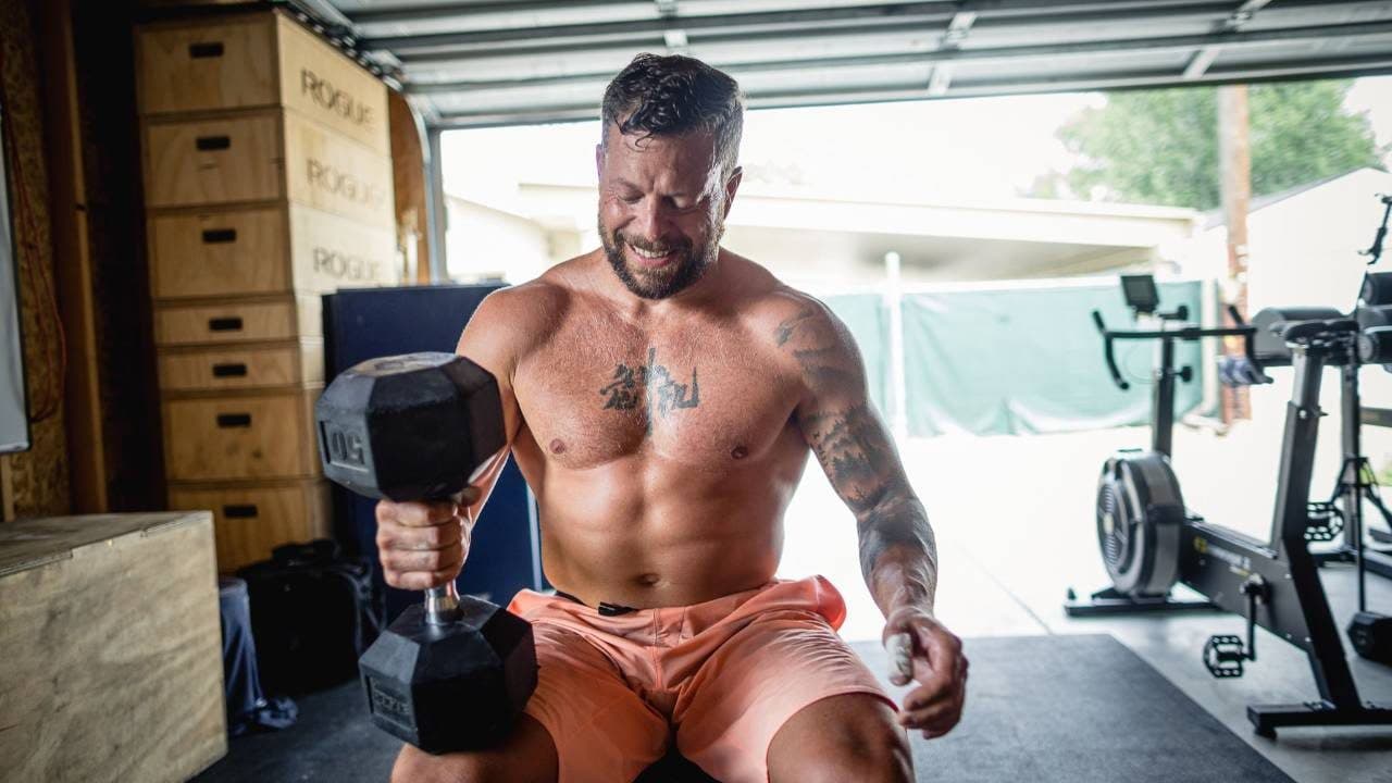 Jason Grubb with a heavy dumbbell in a garage gym