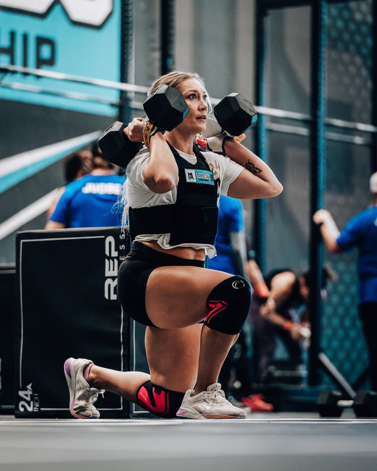 Athlete in a weight vest lunging with two dumbbells