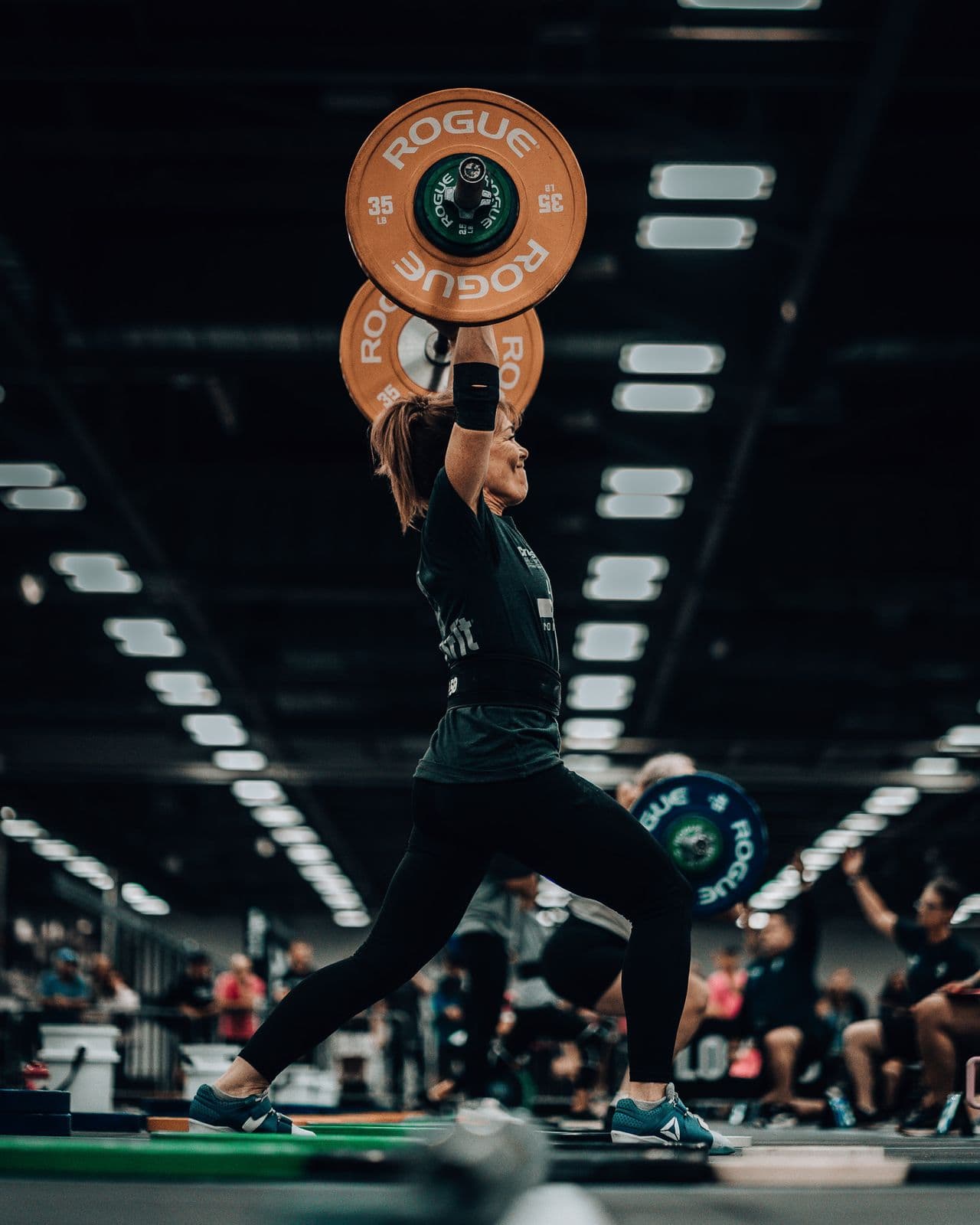 Athlete catching a snatch in a competition arena